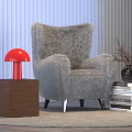 Red Table Lamp on Brown Cube Base Beside Gray Furry Armchair and Stack of Books