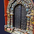 Intricately Carved Black Entrance Gate With Red Brick Walls And Colorful Decorations