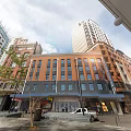 Modern Urban Hotel Building With Orange Exterior Large Windows And Street Storefronts