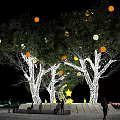Illuminated Trees with Hanging Light Decorations at Nighttime People Gathered Underneath and Bright Trunks