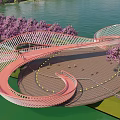 The Modern Red Curved Bridge With Purple Flowering Trees River Grassland And Pedestrians
