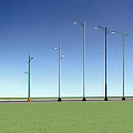 Variety of Outdoor Street Lights Along Roadside with Green Grass and Blue Sky
