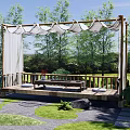 Courtyard Garden Design With Wooden Deck Canopy Curtains Surrounding Trees Grass And Stone Path