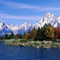 Breathtaking Mountain Lake Scenery With Blue Sky Snow Capped Peaks Colorful Trees And Grassy Shore