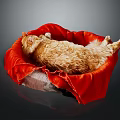 An orange cat lying comfortably in a soft red pet bed against dark background