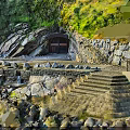 Natural Rocky Cliffside with Cave Entrance Stone Steps and Waterfront Green Vegetation
