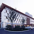 Modern Hotel Building With White And Brown Facade Large Glass Windows Trees And Parking Area
