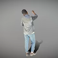 Man Raising Hand Holding Phone Wearing Gray Shirt Blue Jeans And Sneakers Against Gray Background