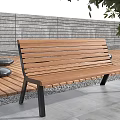 Wooden Outdoor Bench With Black Metal Legs On Deck By Gray Stone Wall And Greenery