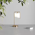 Modern Table Lamp With Golden Base White Lampshade Green Leaves Gray Tabletop And Stacked Books