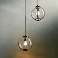 Two Glass Globe Pendant Lights Hanging Against Gray Wall With Illuminated Bulbs