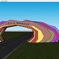 Multicolored Arched Entrance Gate with Rainbow Design and Green Fields Along Long Road