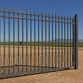 Black Metal Fence With Decorative Spiked Top And Curved Patterns In Rural Field