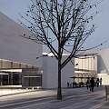 Bright Modern Commercial Street With White Geometric Buildings Outdoor Seating And Trees