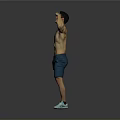 Shirtless Muscular Man Flexing Muscles In Blue Shorts And Green Sneakers Against Gray Background