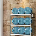 Stainless Steel Multi Tier Storage Rack With Blue Water Jugs In Kitchen Against Brick Wall