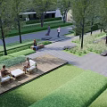 Serene Garden Landscape with Trees Lawn Wooden Deck and Outdoor Seating near High Rise Apartments