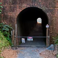 Road Infrastructure Featuring Brick Tunnel Entrance With Metal Gate Warning Signs And Green Vegetation