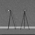 Two Black Tripod Floor Lamps Placed Against Gray Wall With Gray Floor And White Baseboard