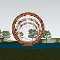 Golden Concentric Ring Sculpture with Inscriptions Surrounded by Trees and Water