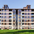 Modern Multi Story Apartment Building Exterior With Green Lawn And Clear Blue Sky