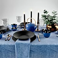 Blue and Black Dinnerware Combination With Gold Candlesticks Green Plant Decor And Elegant Table Setting
