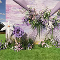 Outdoor Floral Installation With Purple White Flowers Green Grass And Blue Sky Backdrop