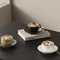 Black Gold White Coffee Cups With Froth And Spoon On Book Dark Table