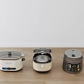 Three Modern Rice Cookers As Kitchen Appliances Placed On Wooden Floor With White Wall Background