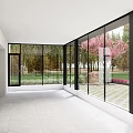 Villa Balcony With Large Glass Walls Overlooking Trees Lawn And Pink Flowers On Tiled Floor