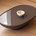 Modern Oval Coffee Table With Dark Smooth Surface And White Bowl On Wooden Floor