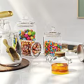 Stylish Ceramic Vessels On Kitchen Counter With Glass Jars Colorful Candies And Green Plants