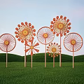 Colorful Windmill Art Installation With Orange Yellow Blades In Green Grass Field