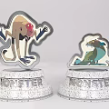 Two Cute Monster Themed Figurine Badges With Statuette Bases Inscribed Monster