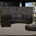 Outdoor Wicker Sofa With Gray Cushions Round Coffee Table And Green Plants By Stone Wall