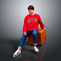 Man Wearing Red Love Me Sweater Sitting on Brown Trunk Blue Jeans White Sneakers