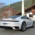 White Porsche Sports Car Parked Outdoor With Building And Mountain View