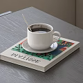 Rich Black Coffee in White Cup on Gray Table with Silver Spoon and Colorful Magazine