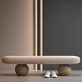 Light Gray Padded Bench with Two Round Wooden Legs and White Shoes Near Gray Wall