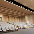 Spacious Conference Room With Wooden Walls Rows Of Seats Projection Screen And Ceiling Lights