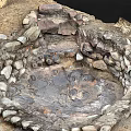 Natural Circular Stone Enclosed Depression With Muddy Ground And Water Puddles