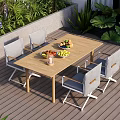 Outdoor Wooden Dining Table With Four Gray Chairs And Fruit Bowls Near Green Plants