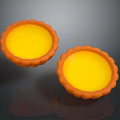 Two Fresh Baked Egg Tarts With Golden Yellow Filling And Orange Fluted Crust