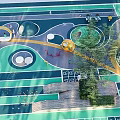 Green Children's Playground With Circular Curved Slides Swings Trees And Seating Areas