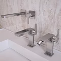 Sleek Modern Bathroom Faucets On White Countertop With Beige Tile Backdrop