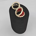 Two Elegant Gold Rings With Red And Black Twisted Design On Black Display Stand