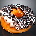 Fresh Glazed Orange Donut With White Drizzle And Black Chocolate Crumbs