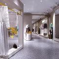 Modern Clothing Store Interior With Clothing Displays Decorative Plants And Lighting Fixtures