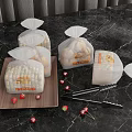 Fresh Bread in Transparent Bags on Black Marble Countertop with Strawberries and Tongs