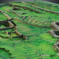 Archaeological Terrain With Green Grass Stone Walls And Ancient Ruined Structures